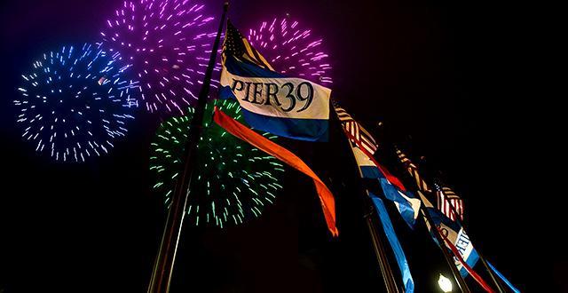 Fireworks light above the flags at Pier 39