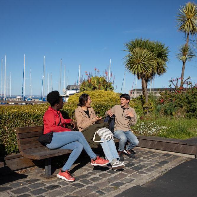 People sitting and chatting on a bench at Pier 39