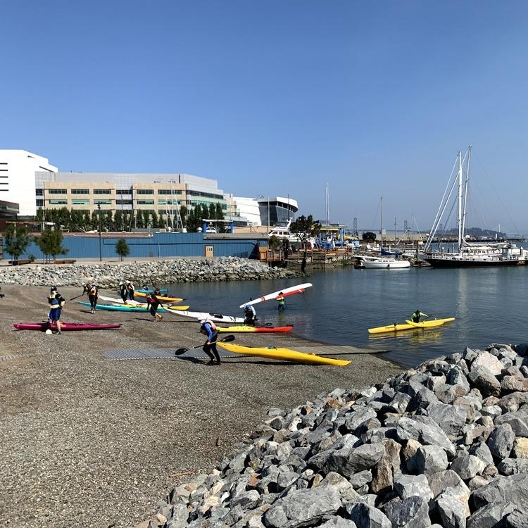 Kayakers prepare vessels to enter the water at Crane Cove Park