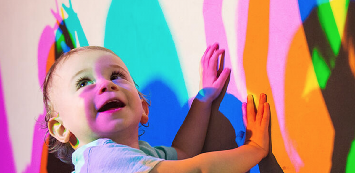 exploratorium_baby_shadows.png A happy baby playing with colorful shadows at the Exploratorium, photo credit to Exploratorium