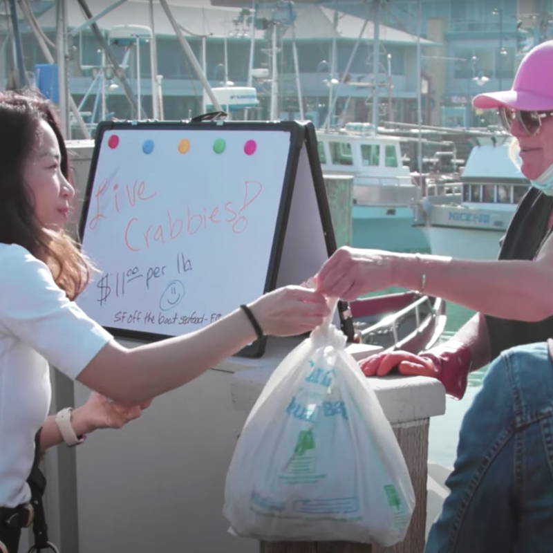 Woman buying fresh crab from fisher at Fisherman's Wharf